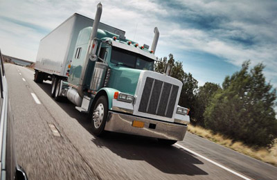 A green semi-trailer truck on a highway.