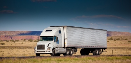 A white commercial semi-trailer truck on a highway.