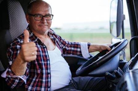 Truck driver giving a thumbs up in his cab
