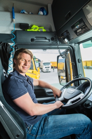 Happy male truck driver smiling in his cab