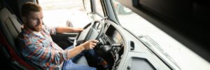 Side view of professional driver behind the wheel in truck's cabin
