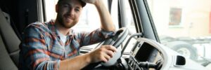 driver behind the wheel in truck cabin.