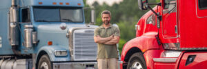 Temporary truck driver standing in front of two trucks
